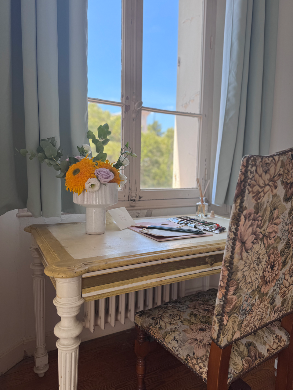 Vintage desk with flowers, patterned chair by sunny window, south of France