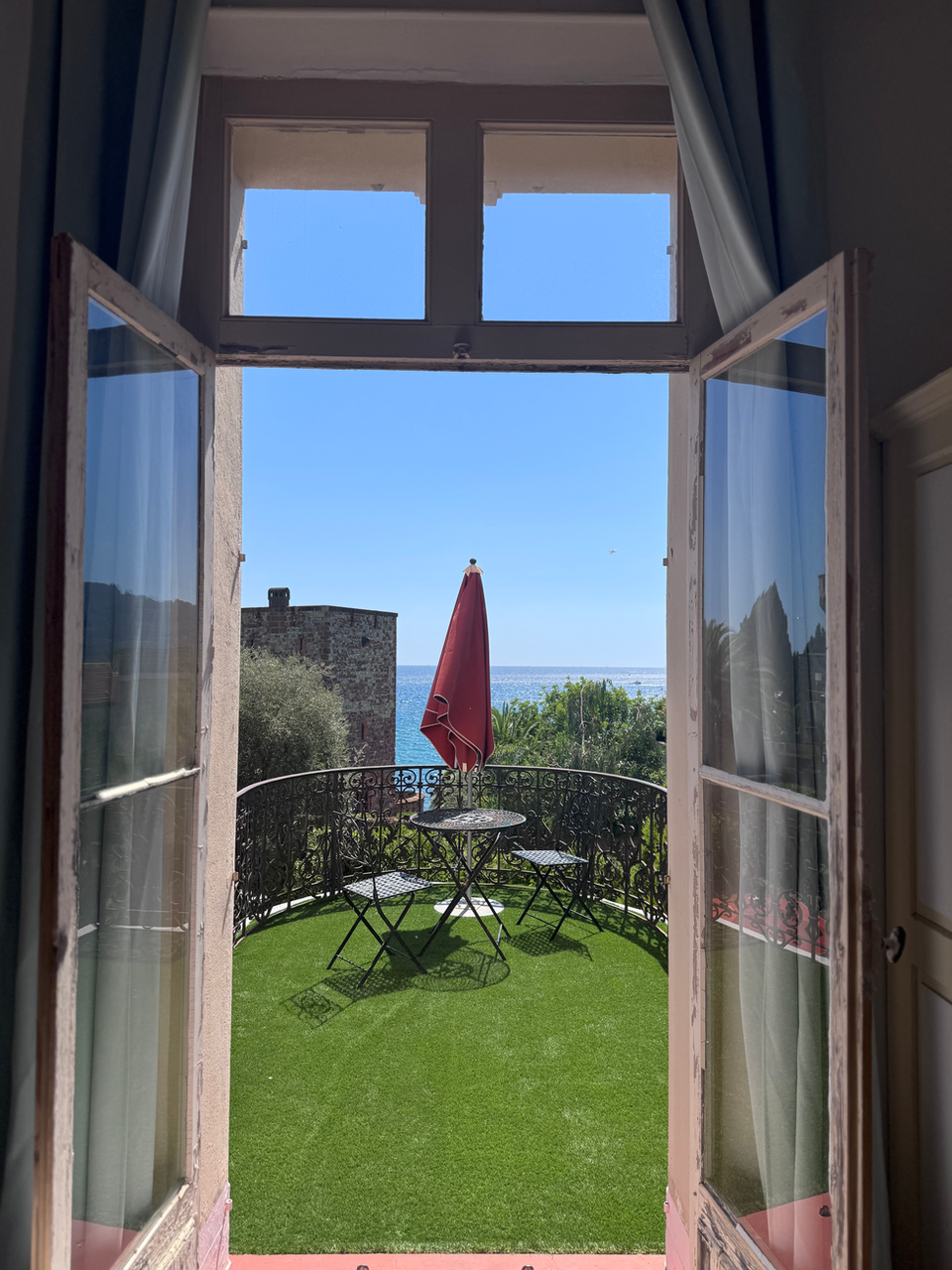 Open balcony doors with blue sea view, accommodations in south of France.