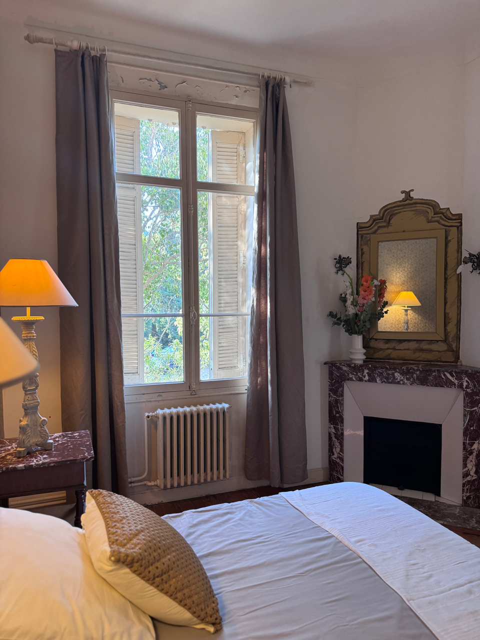 Cozy bedroom with fireplace and window, ideal accommodations in south of France.