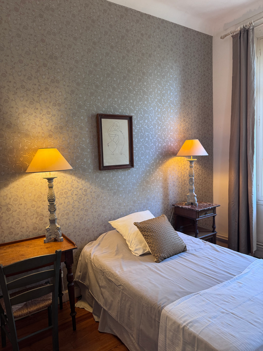 Hyggeligt soveværelse med enkeltseng, to lamper, tapet, indkvartering i Sydfrankrig.