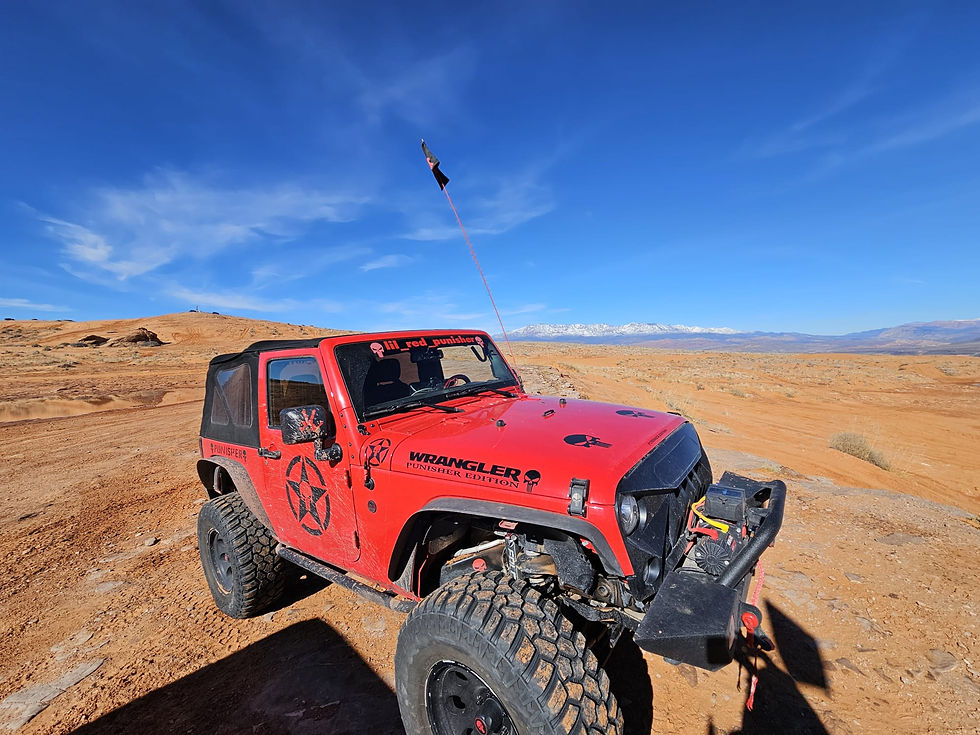 Close-up view of an off-road vehicle tire on a rocky trail with red rocks in the background