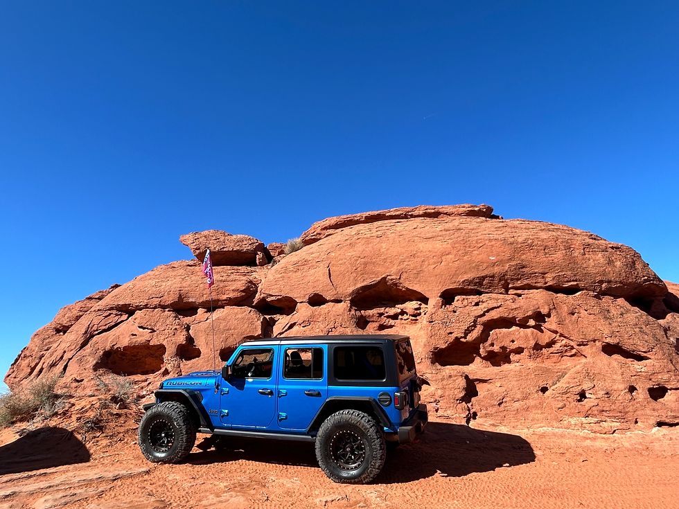 Wide angle view of a 4x4 vehicle parked at a scenic overlook with red rock canyons in the background