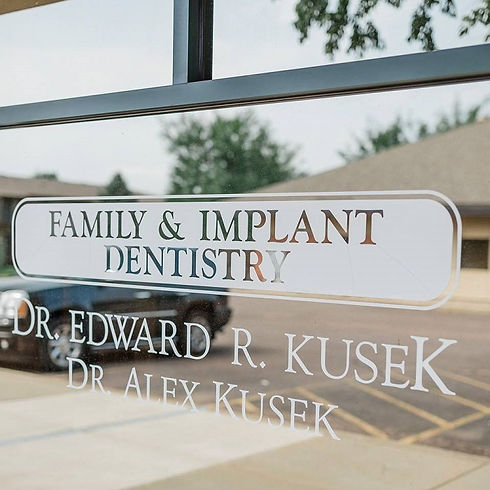 Signage on the glass pane at Kusek Family & Implant Dentistry Sioux Falls SD.jpg