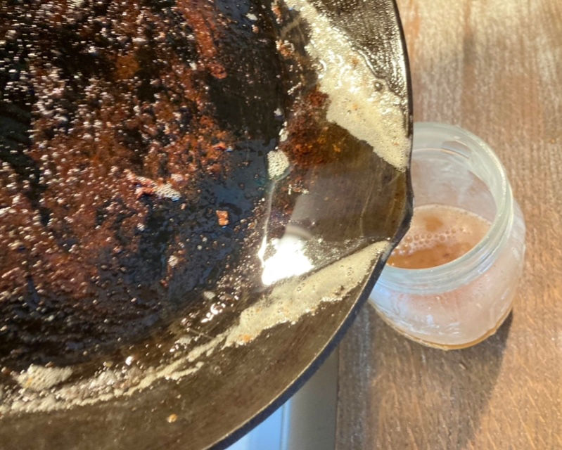 Pouring off excess grease into Mason jar after pulling cooked bacon from the pan.
