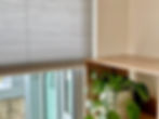 A corner of a room with a shelf and honeycomb pleated blind dressing the window