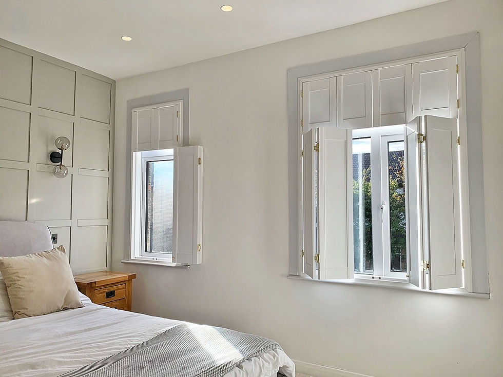White wooden solid pannel shutters half open in a white bedroom