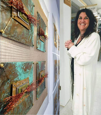 Female artist standing with hands clasped in front of metal and wire sculpture