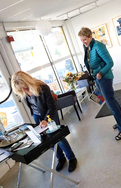 two fine art collectors sign-in to front desk in gallery