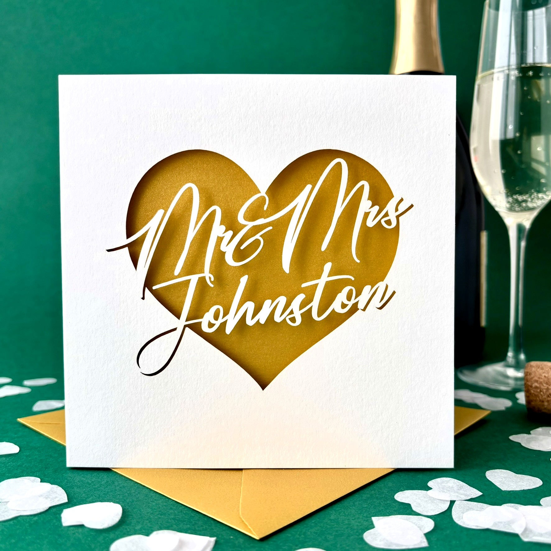 White laser cut wedding card. Heart shape personalised with Mr & Mrs plus surname text in script, with a gold paper insert.