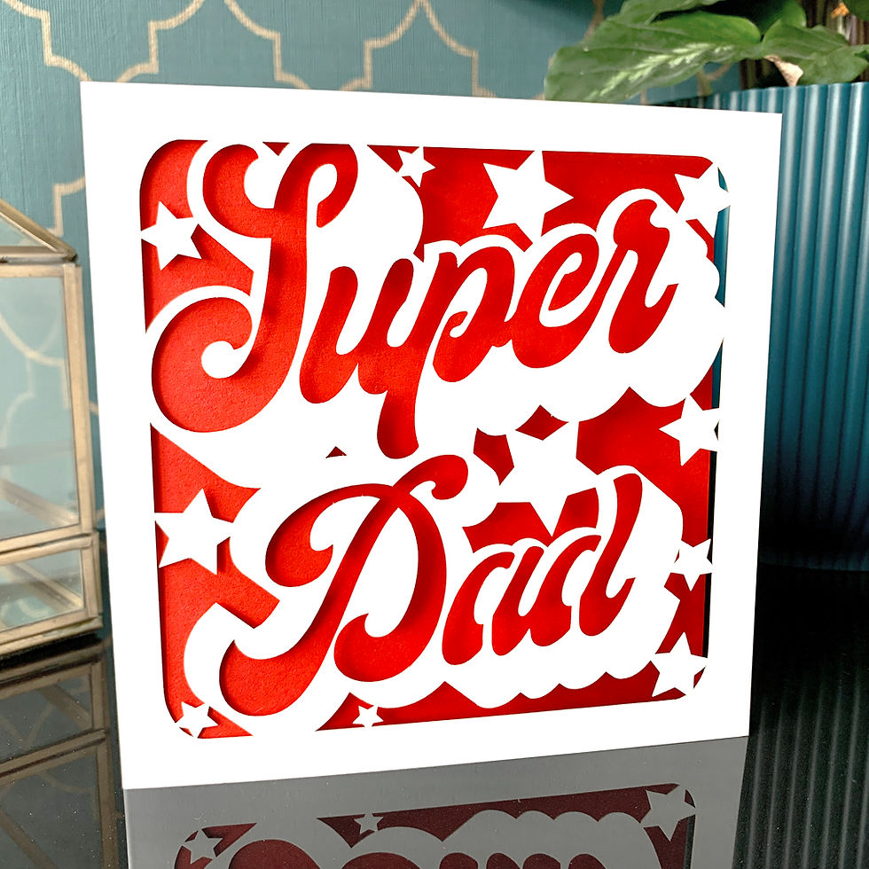 White laser cut Father's Day card, reading Super Dad in a bubble font with stars around, with a red paper insert.