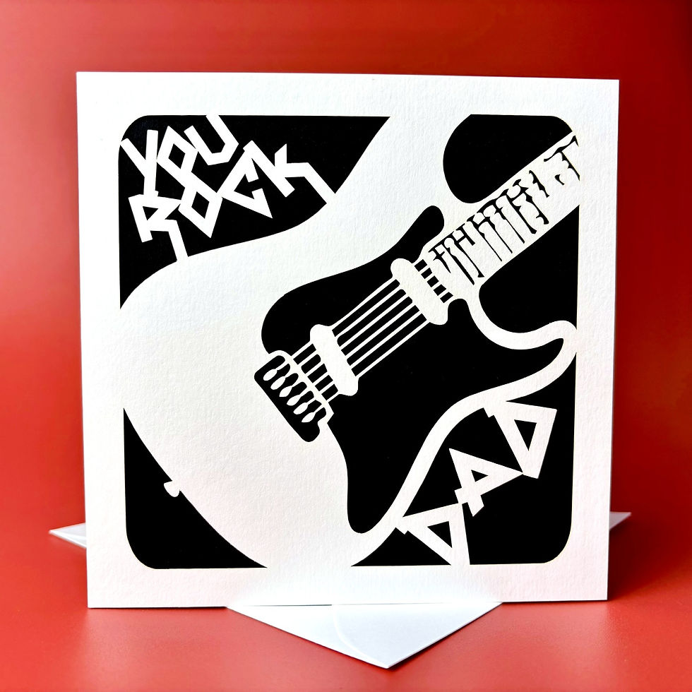 White laser cut Father's Day card, with a guitar design reading You Rock Dad, with a black paper insert.