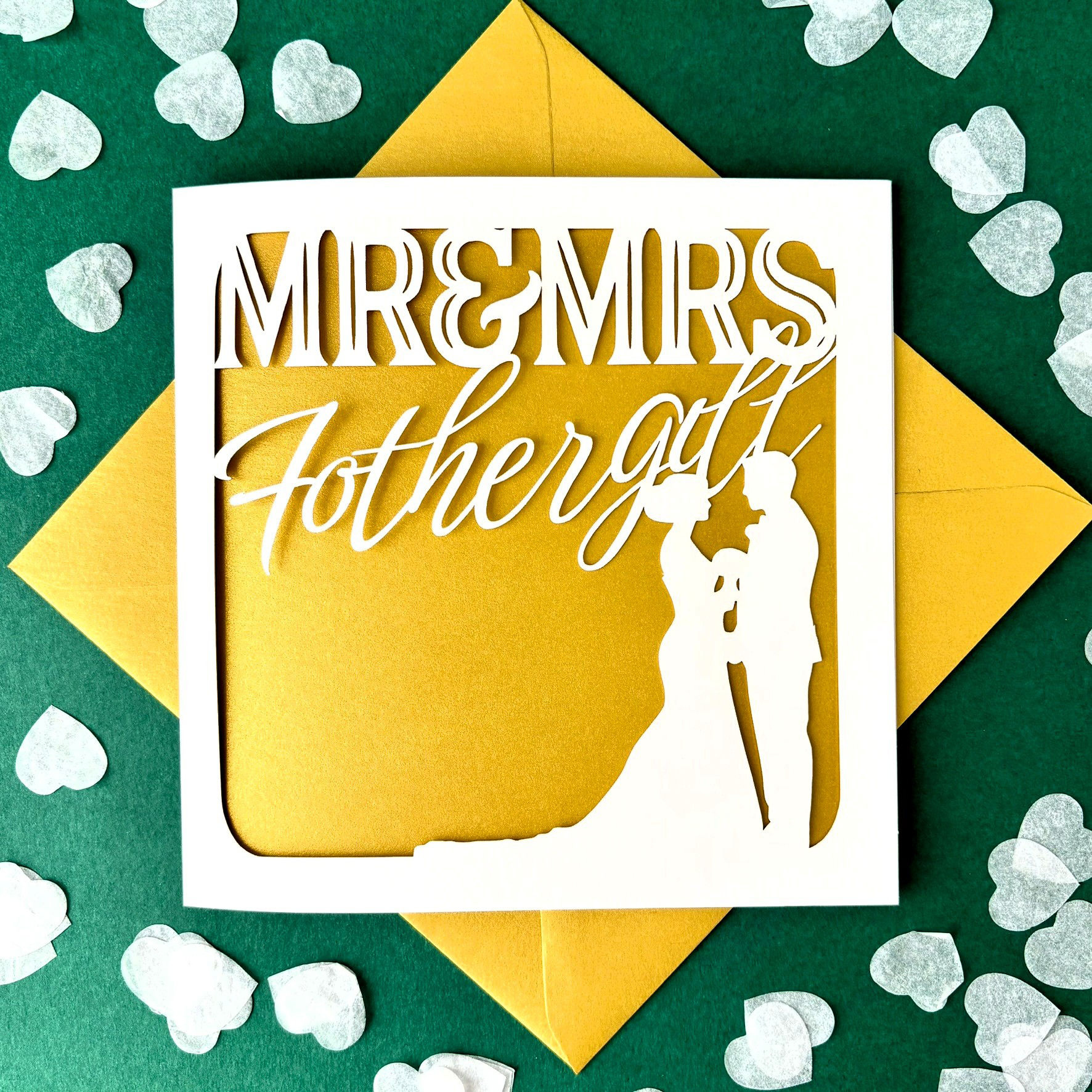 White laser cut wedding card. Silhouette of bride & groom, 'Mr & Mrs' and personalised surname, with a gold paper insert.