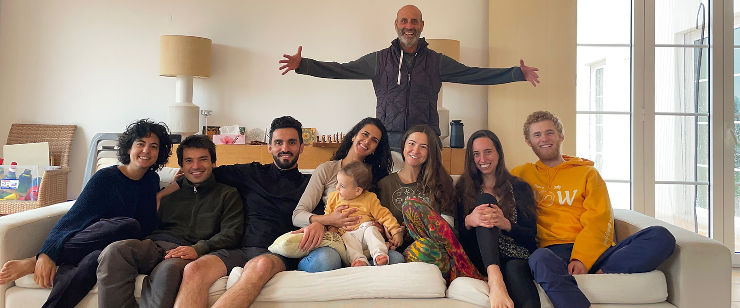 Community portrait, everyone is smiling. man stands behind with spread arms