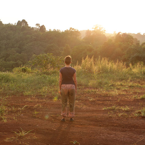 a woman practicing standing meditation at sunset in nature 