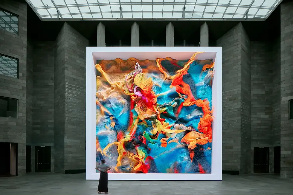 Visitatrice di fronte a una monumentale opera d'arte generativa di Refik Anadol. Flussi di colori vibranti creati dall'Intelligenza Artificiale, analizzati nel saggio filosofico di Silvia Torricelli.