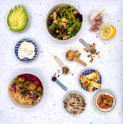 a marble platter of salad bowls, proteins, sprinkles and measuring spoons