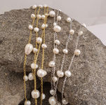 Multiple rows of handmade silk jewelry with freshwater pearls and gold leaves displayed on a gray stone.