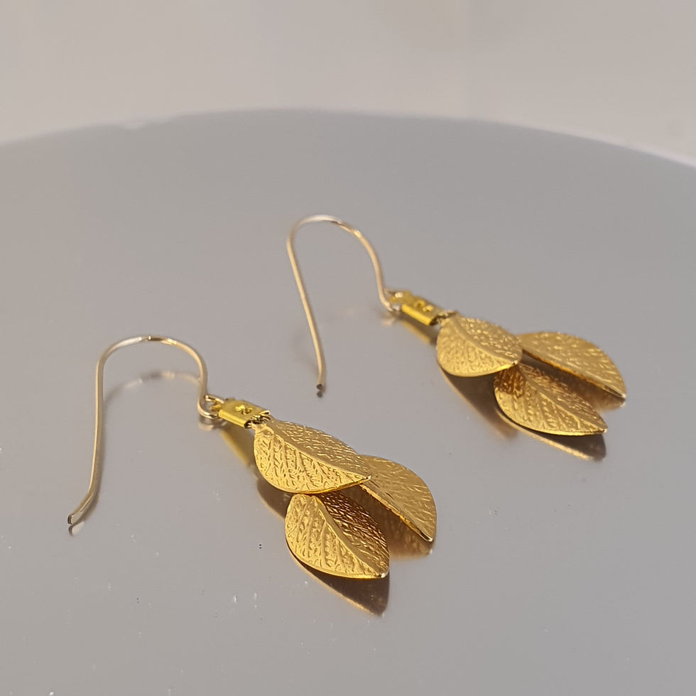 Thumbnail: Short gold leaf earrings with silk threads placed on a display surface 2