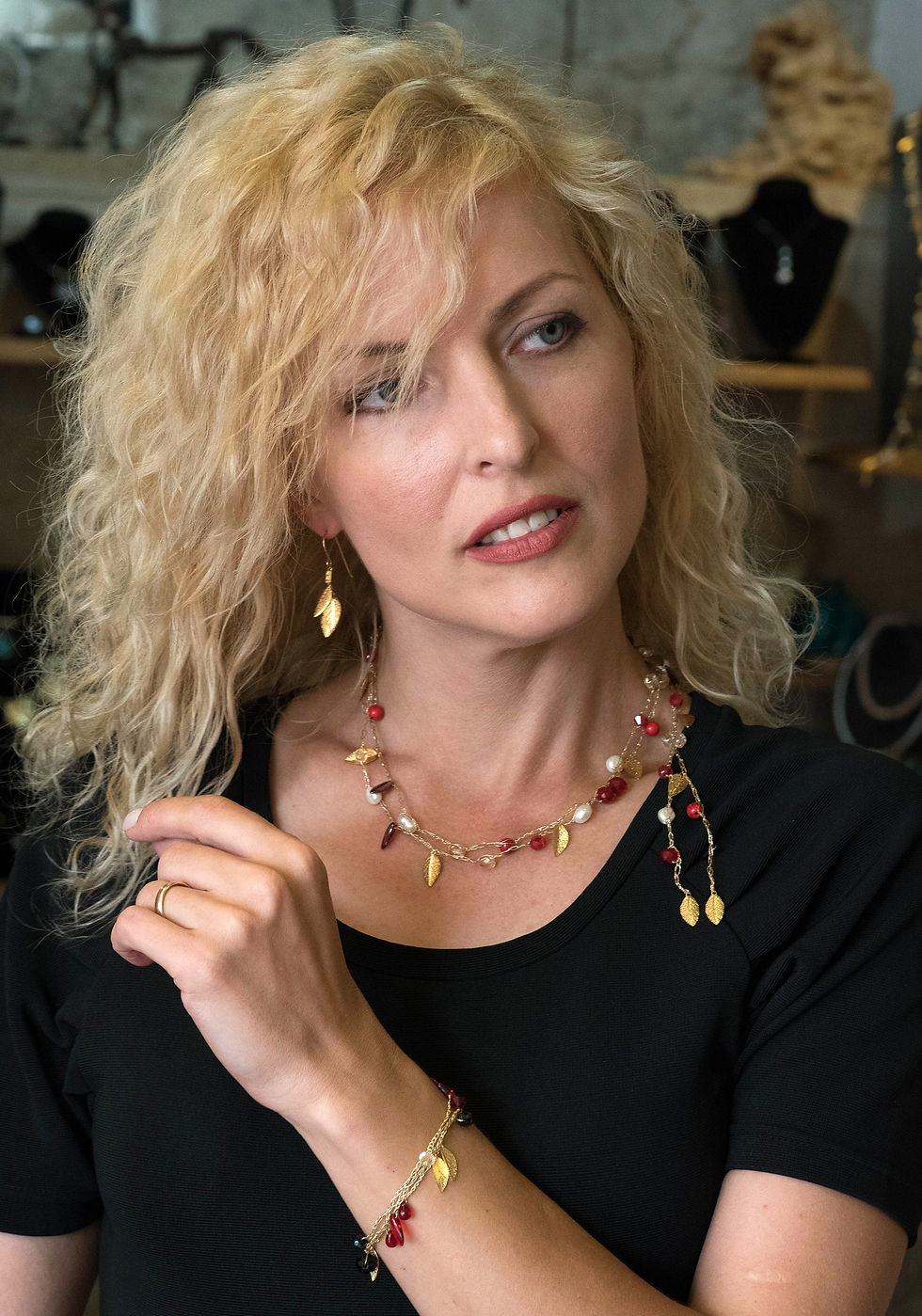 A model wears a handmade gold silk necklace with gold leaves and red crystals