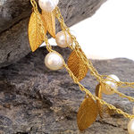 Macro shot of a handmade silk necklace with gold leaves and freshwater pearls, unique Israeli designer jewelry.