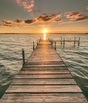 A sun setting at the end of an ocean pier