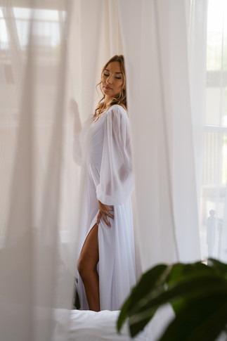 woman standing  in wedding dress in neutral-toned room with soft light