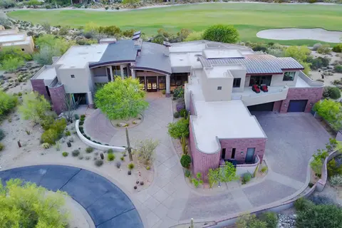 Aerial exterior view of a custom luxury home in Arizona, showcasing contemporary desert architecture, expansive residential design, and golf course surroundings.