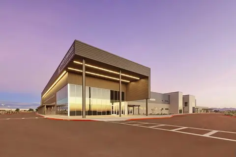 Modern educational building, featuring the illuminated entrance of the Applied Technologies high school at sunset with a glass facade.