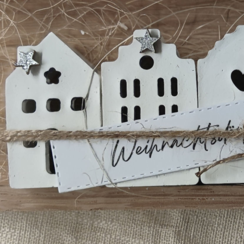 Vier Miniaturhäuschen aus Gips aneinandergereiht. Verziert mit einem kleinen silbrigem Stern.