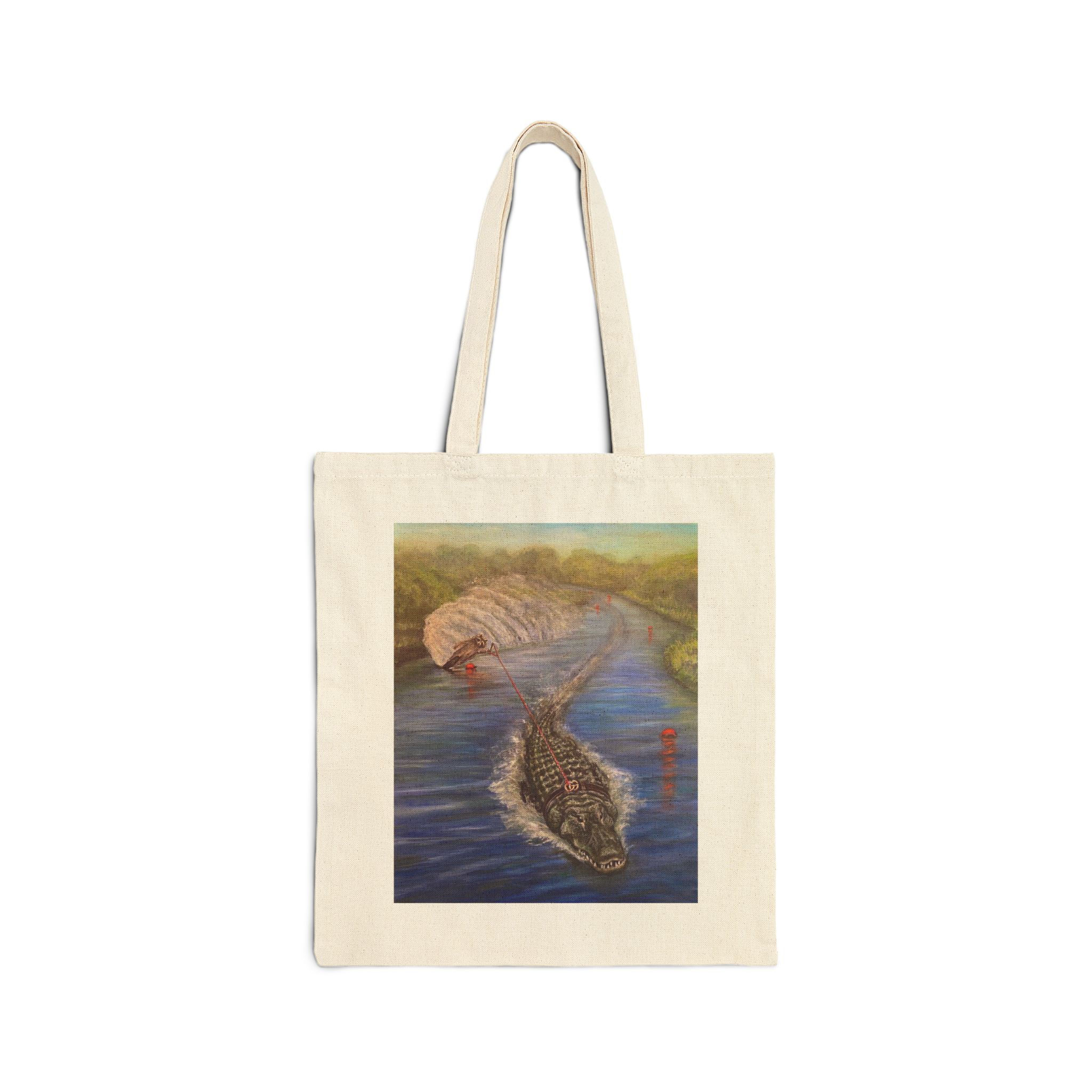 Raccoon water ski behind an alligator on the RiverCotton Canvas Tote Bag.