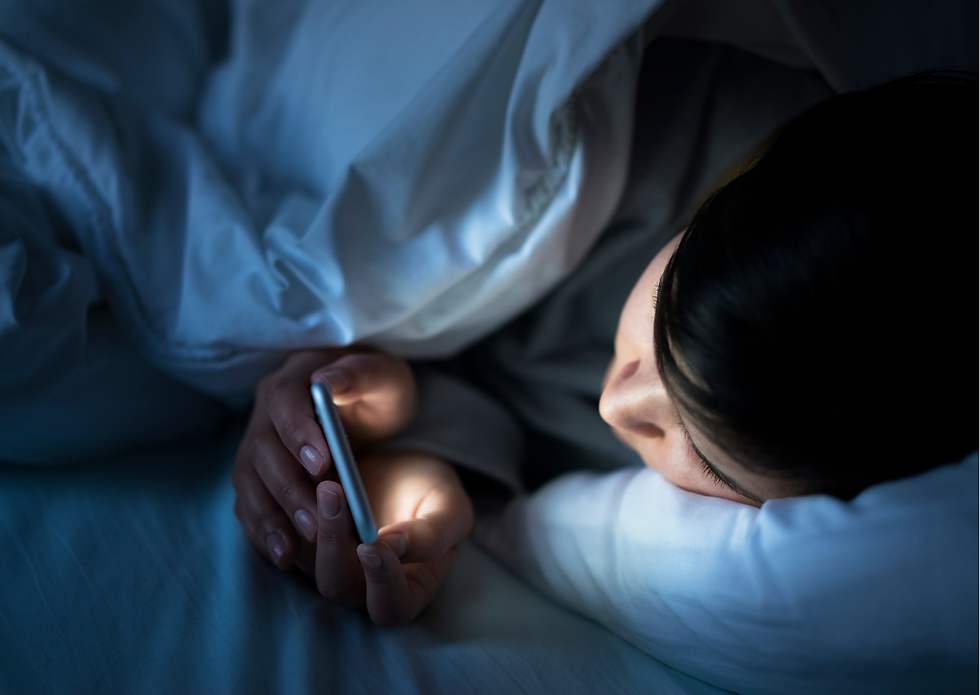 Frau im Bett am Smartphone mit Blaulicht, das die natürliche Entspannung stört, statt das Nervensystem vor dem Schlafen zu beruhigen.