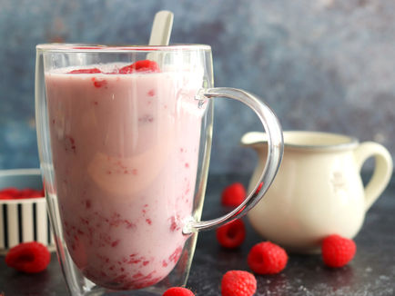 Raspberries lightly mashed with sugar and milk in a glass mug