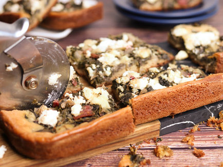 Sliced summer greens and feta pie on a wooden cutting board