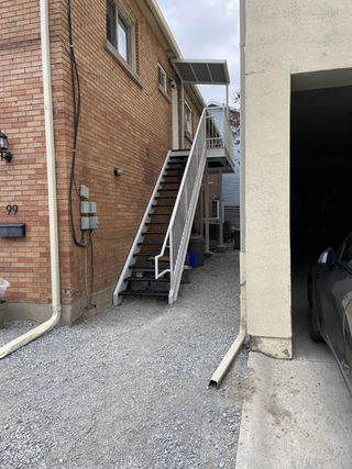 Second storey rental unit steel access stairs painted limestone with black bolt on bar grating treads.