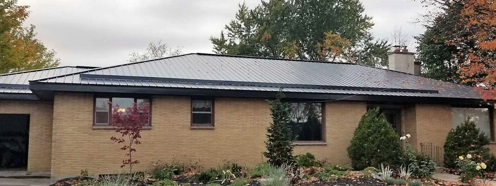 Newly installed black steel roof with snow guards on a brown brick bungalow.
