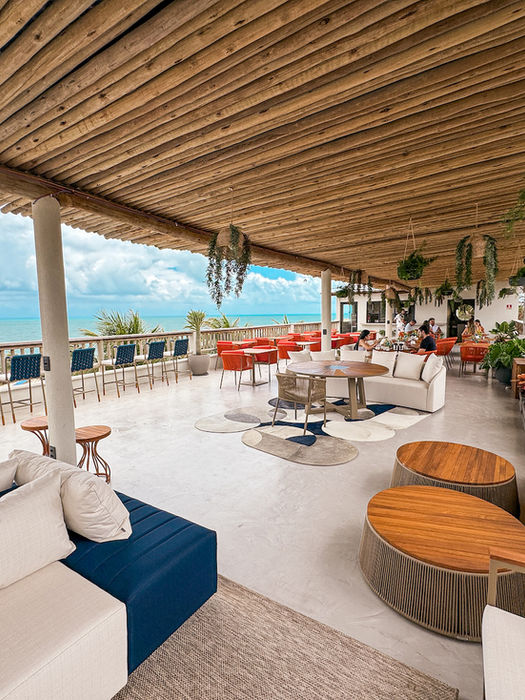 lounge com mesas, sofás e puffs no Poozendin com vista para o mar de Canoa Quebrada-CE