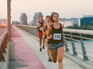 Woman runner smiling at the finish line of a marathon event, wearing a bib and medal, symbolizing her journey from local runs to ultra marathons.