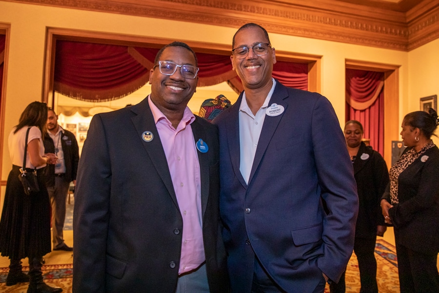 Two cast members smiling in the Main Street Opera House lobby