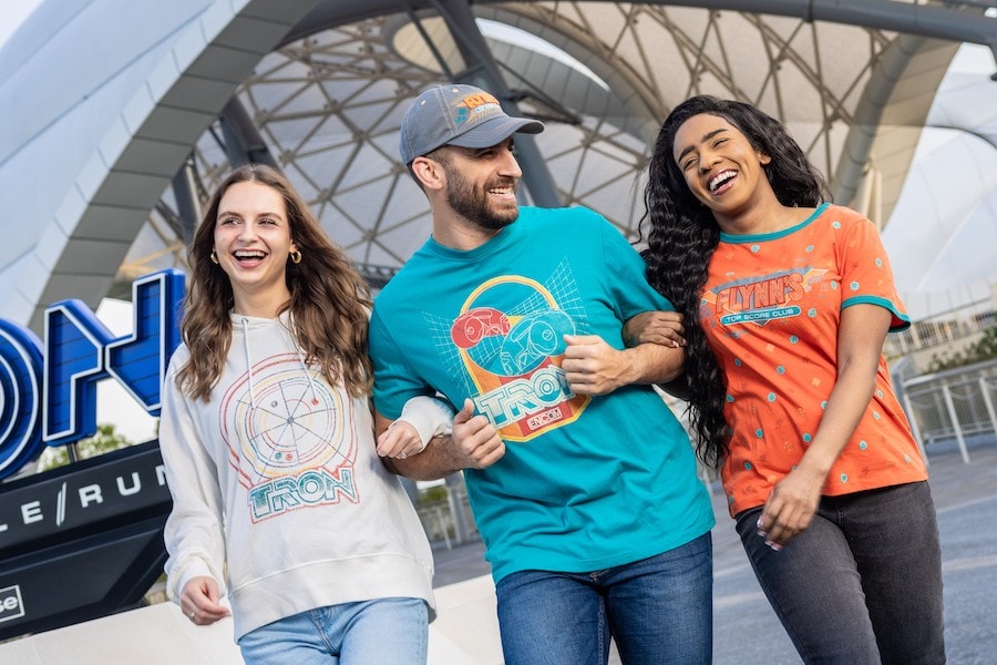 Three people walking by TRON Lightcycle / Run wearing 1980s-inspired TRON apparel