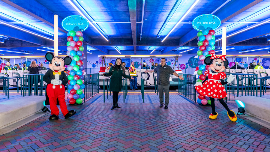Mickey and Minnie Mouse with cast members boarding the parking trams in background