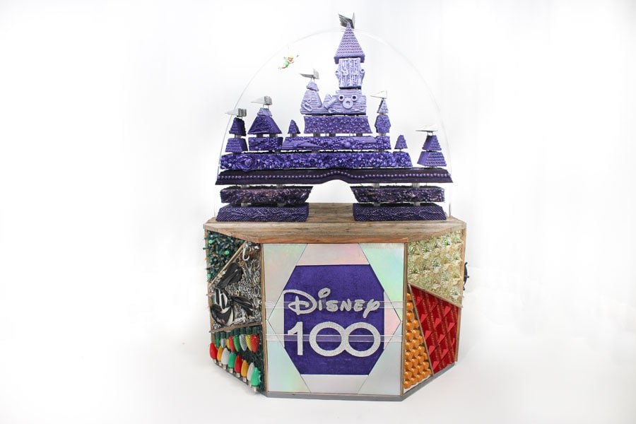 A Disney100 display made from recycled materials featuring Tinker Bell flying over Sleeping Beauty Castle