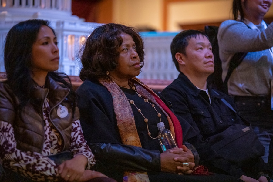 Carmen Smith sitting among cast members watching the video
