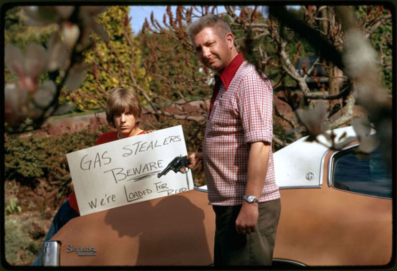Father and son hold up their sign saying Gas Stealers beware during the 1973 Oil Crisis