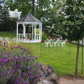 White gazebo decorated with flowers in the Mediterranean garden at Lake Hill Estate with event chairs set up Auckland