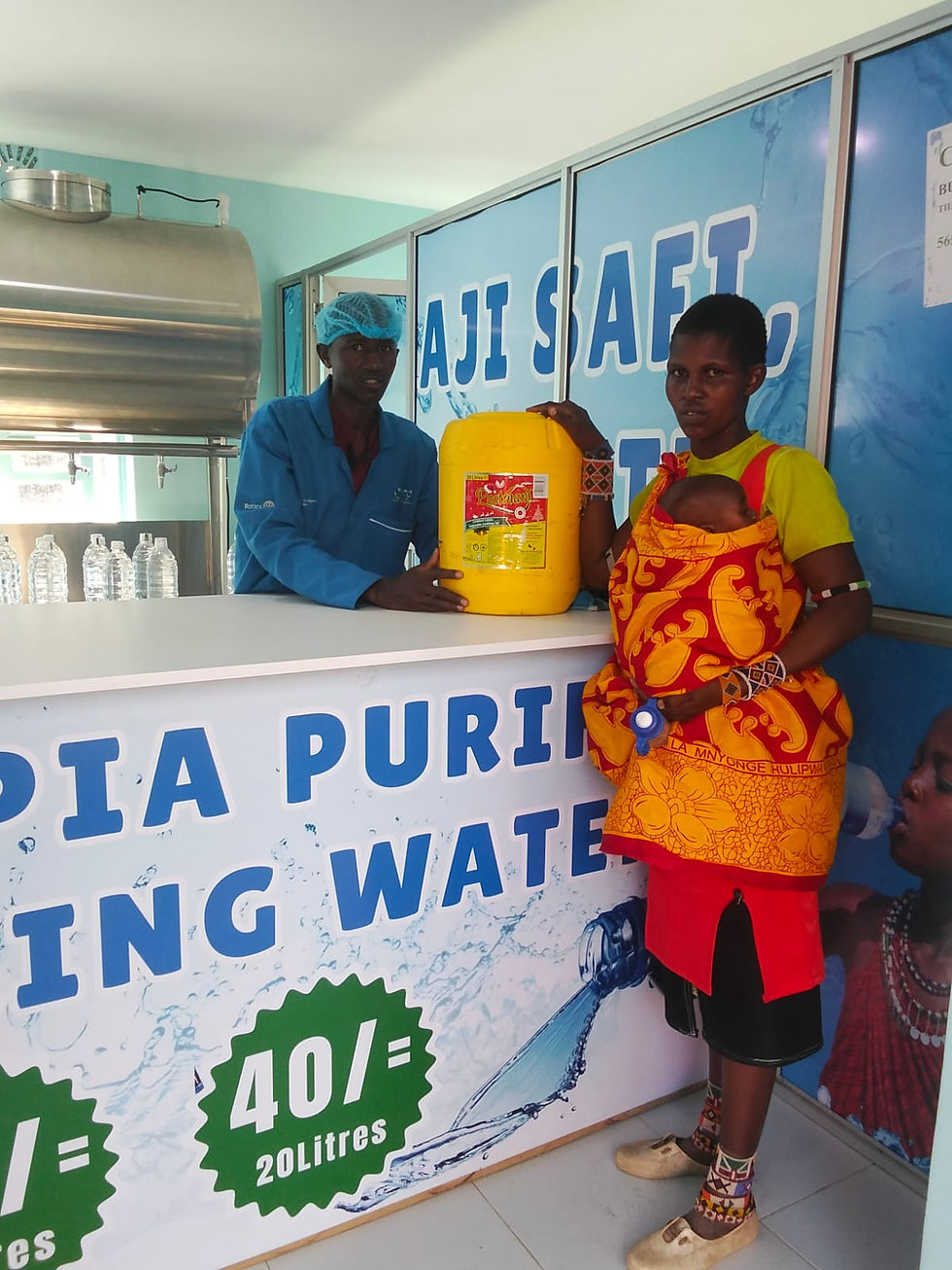A mother and baby who presented for treatment of a water-borne illness are sent home with clean water from the newly launched water project at the clinic.