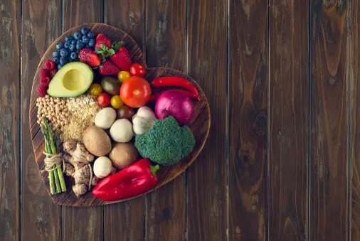 heart shaped board full of foods high in fibre like avocado, broccoli, pepper, and fruits