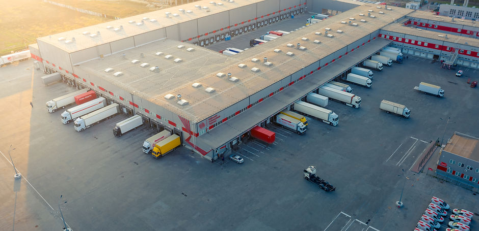 Aerial view of a logistics park with warehouse, loading hub and many semi trucks with carg