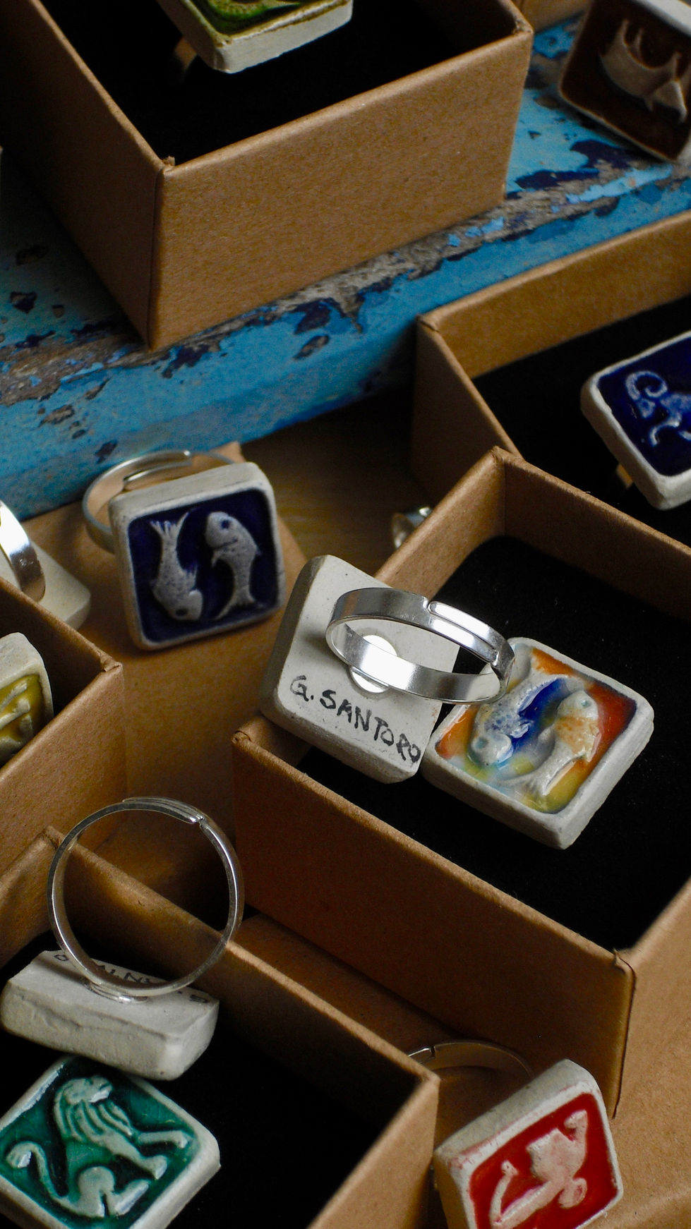 Un primo piano di anelli della collezione Zodiaco con montatura in argento 925, uno dei quali mostra la firma ‘G. Santoro.’ | Close-up of Zodiac rings with adjustable 925 silver bands, one of which features the signature ‘G. Santoro.’ | Primer plano de anillos de la colección Zodiaco con montura ajustable de plata 925, uno de los cuales muestra la firma ‘G. Santoro.’