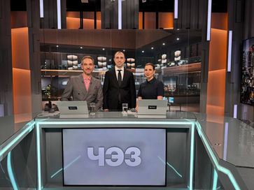 Loran Jacobs and television presenters standing and posing together on a modern broadcast studio set.