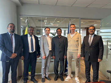 Loran Jacobs and Wegagen Bank executives posing together in a bright, modern corporate lobby.